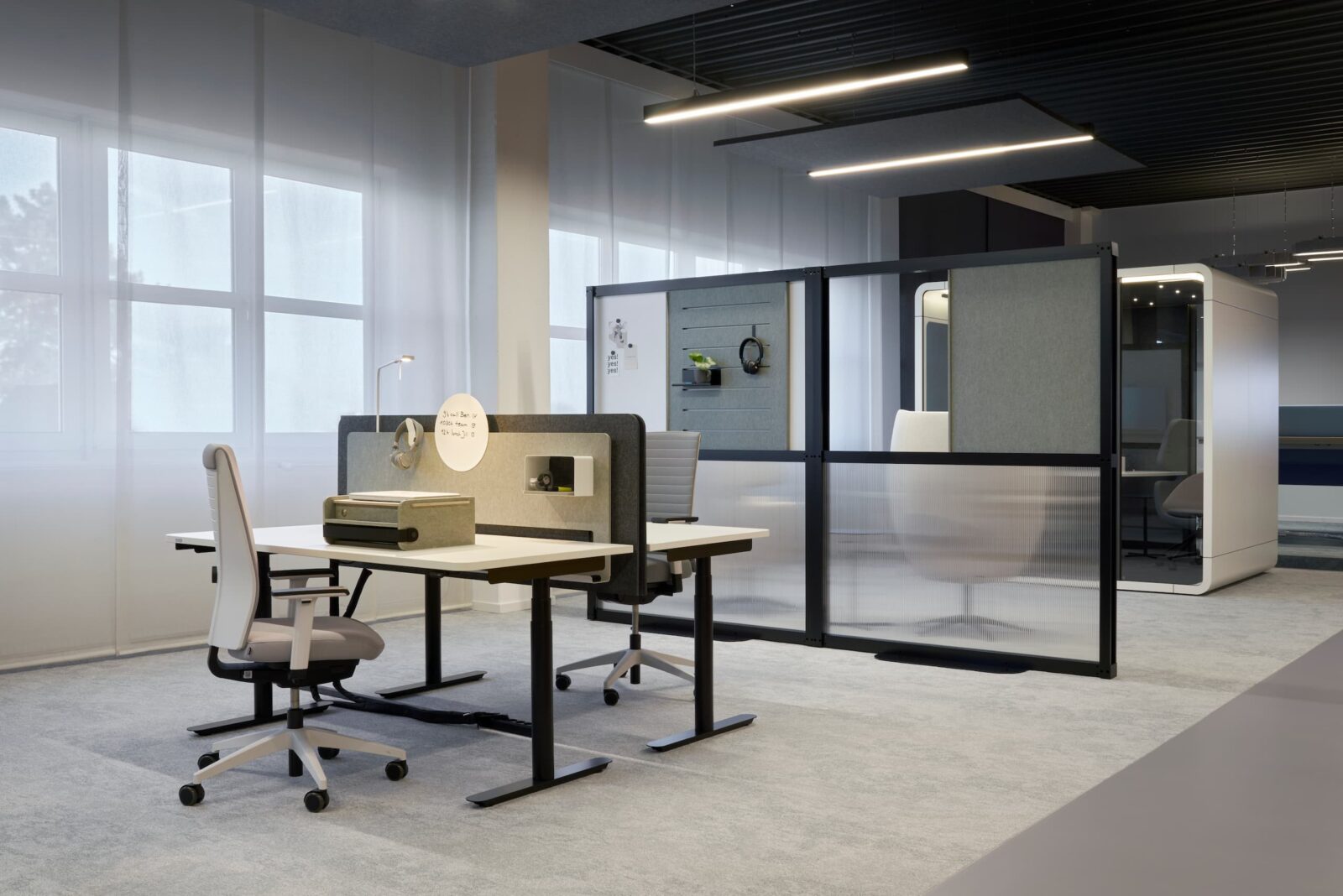 Blick in das Fleischer Work Lab mit Fokusarbeitsplätzen, Stellwänden und einer Raum-in-Raum Lösung als Meetingraum.